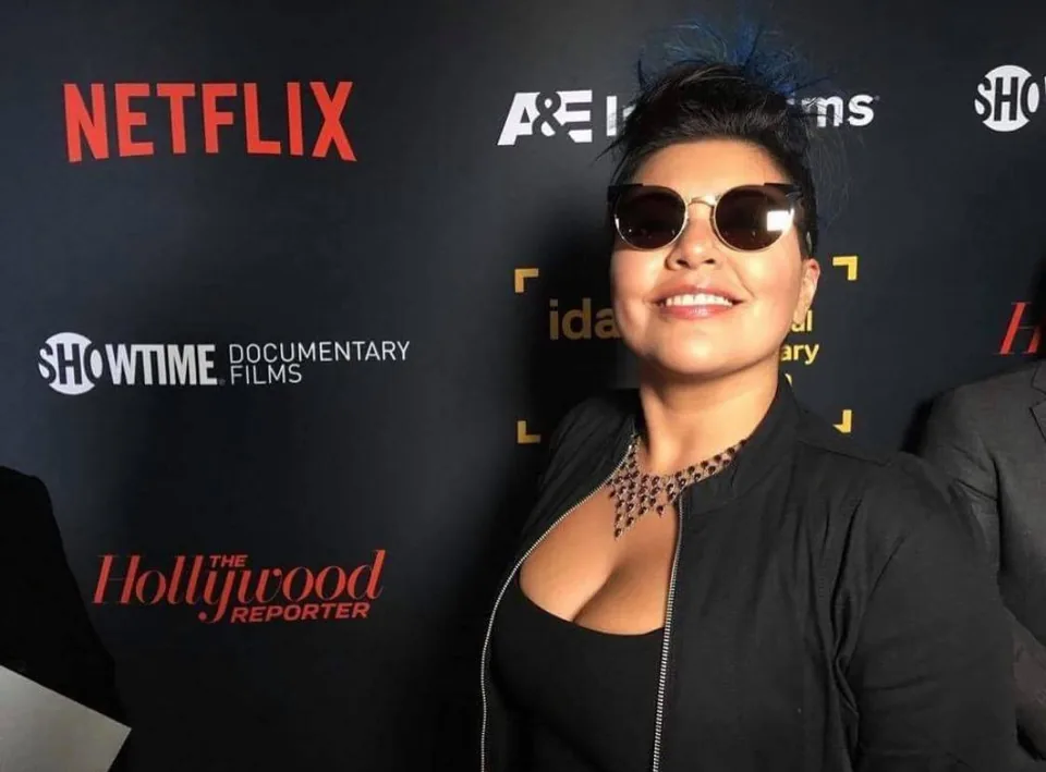 A woman in sunglasses at a press wall with the names of Netflix, A&E, Showtime and The Hollywood Reporter.