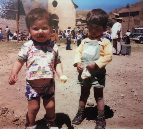Dos niños pequeños de pie en una calle polvorienta, en una fotografía antigua a color.