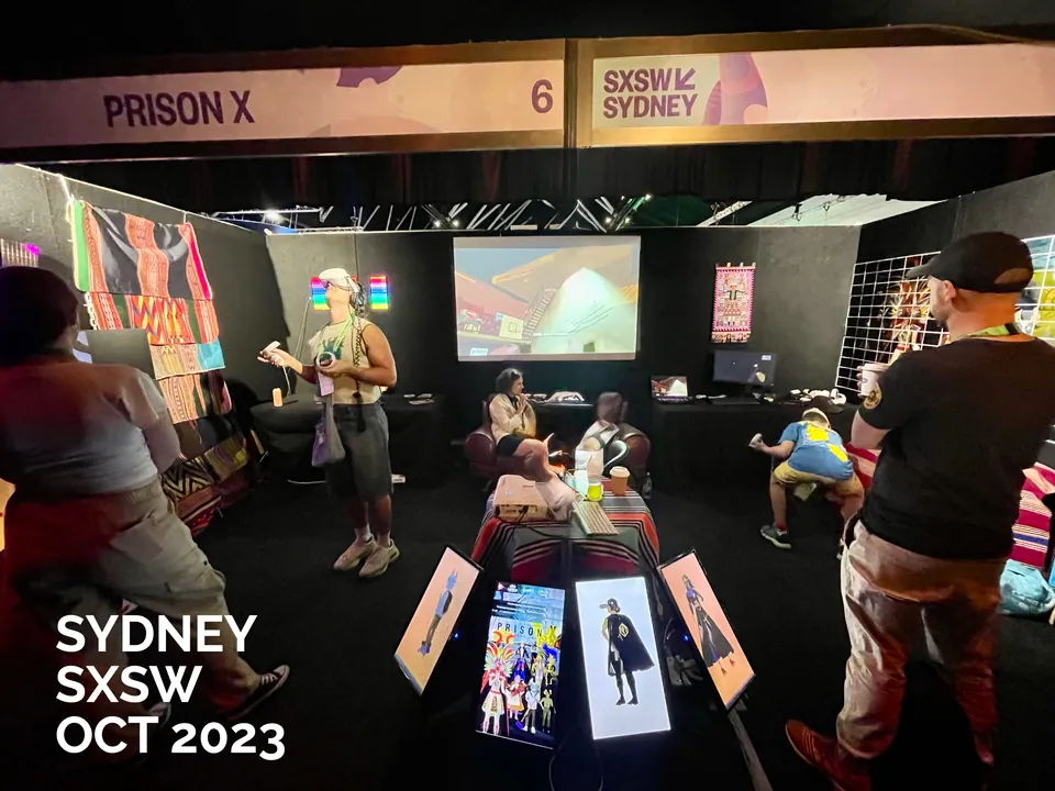 Visitantes con visores de realidad virtual en un stand con obras de Prison X colgadas. SXSW Sydney, octubre de 2023.