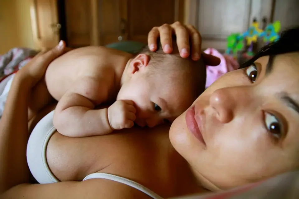 Una madre está acostada junto a su bebé recién nacido.