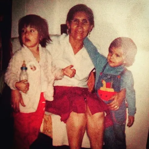 Una abuela sostiene a un niño pequeño, con otro niño a su lado.