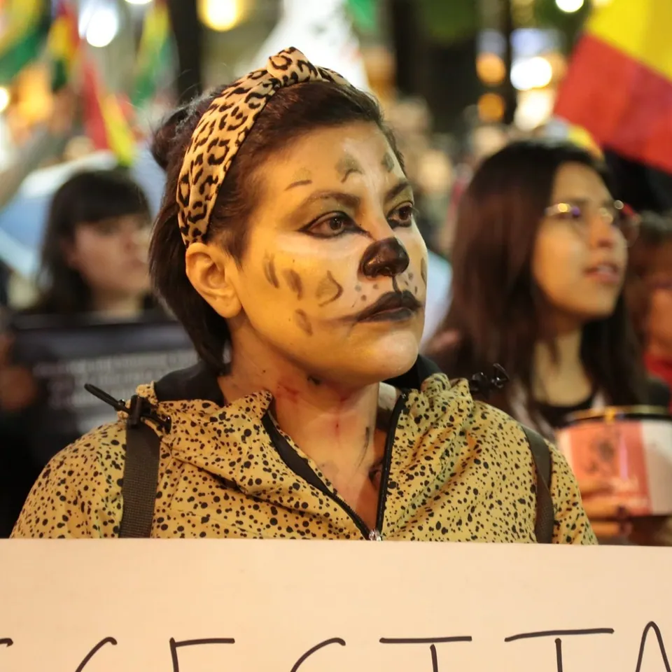 Una mujer con la cara pintada de jaguar y una vincha con estampado de leopardo, en una protesta.
