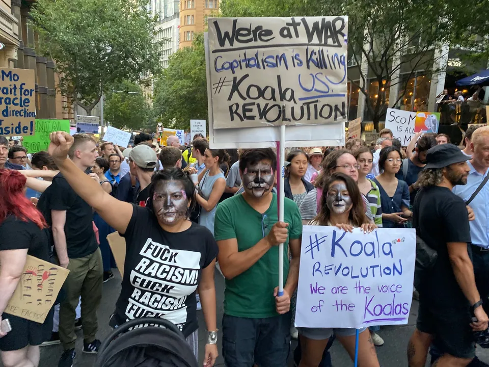 Manifestantes en Sídney, algunos con la cara pintada, llevan carteles que dicen Koala Revolution.