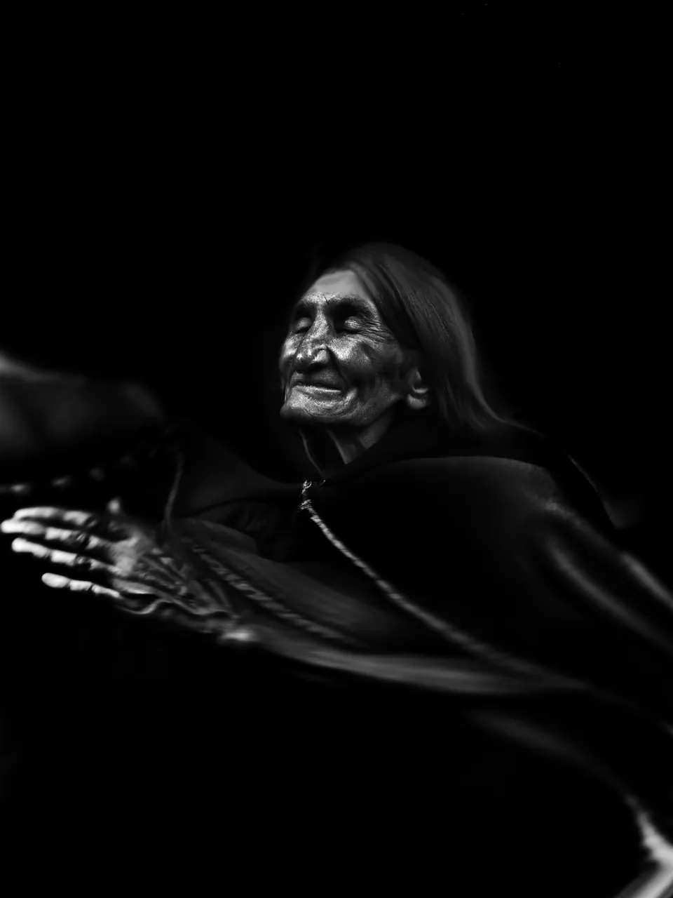 Un retrato hecho con IA, en blanco y negro: una anciana andina extiende la mano desde la oscuridad.